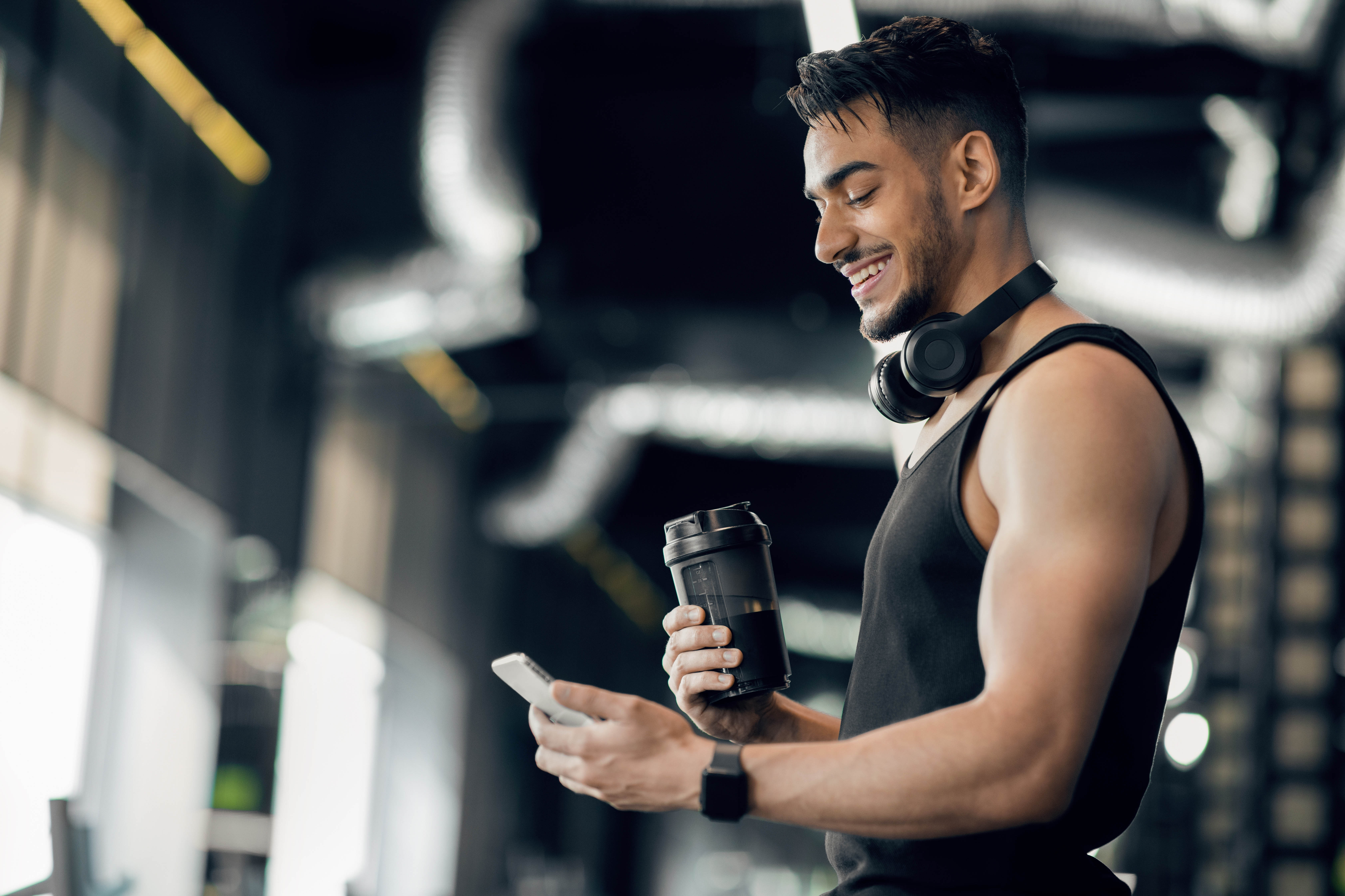 Young man checking his phone in the gym